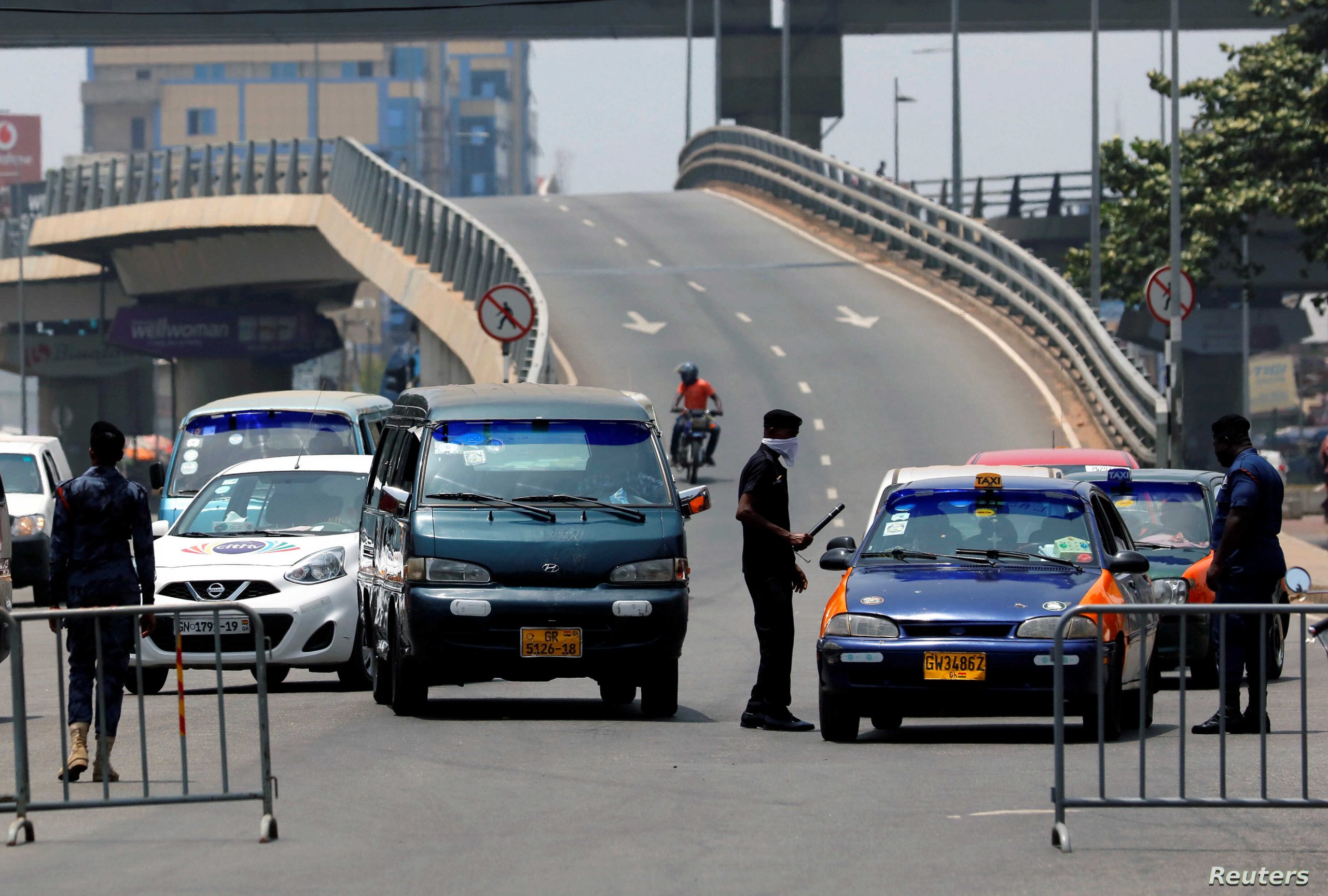 A police officer controls a car at a roadblock to restrict inter-city movement during partial lockdown in the cities of Accra and Kumasi to slow the spread of the coronavirus disease (COVID-19), in Circle neighborhood of Accra